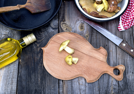 fresh edible wild mushrooms, olive oil and black round cast-iron frying pan on a gray wooden background,の写真素材