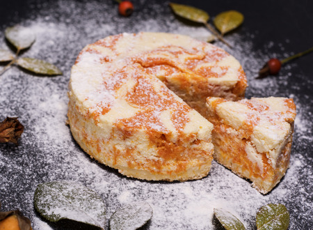 round cheesecake with pumpkin sprinkled with powdered sugar on a black background, top viewの写真素材