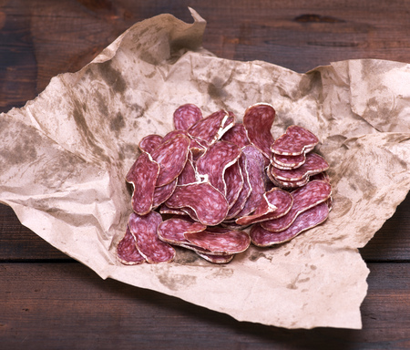 sliced smoked salami on brown paper, top viewの写真素材