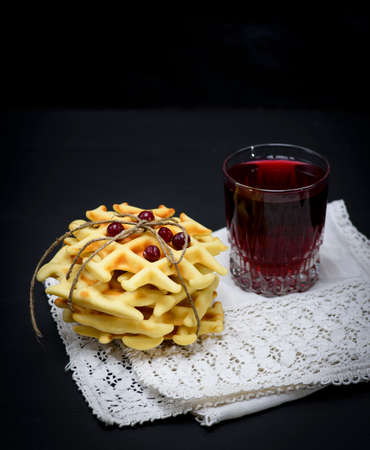 baked Belgian waffles and fruit compote in a glass on a black backgroundの写真素材