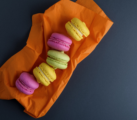 multicolored macarons on an orange napkin, empty space on the right, top view