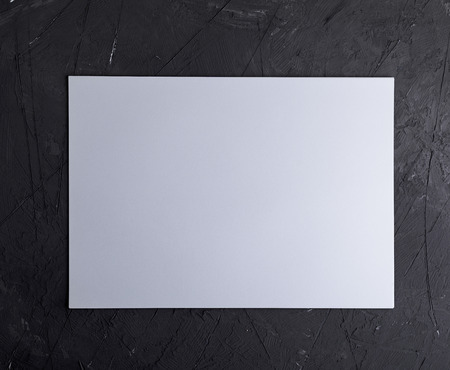 rectangular white blank sheet of paper on a black textural background