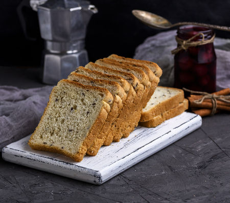 Square pieces of bread from white wheat flour with flax seeds on a wooden board