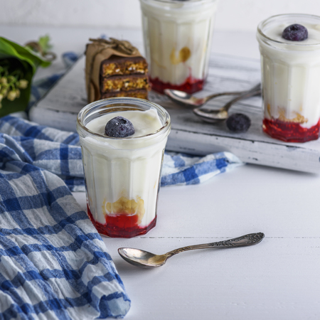 homemade yogurt in transparent glass with syrup and banana on a white wooden background, top viewの写真素材