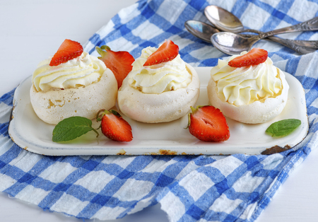 round baked meringue pie with strawberries on a blue textile napkin, close upの写真素材
