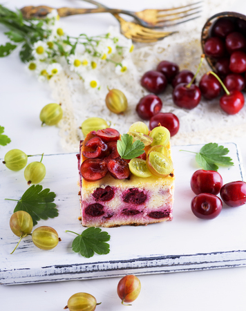 piece of pie from berries of cherry and cottage cheese, decorated with fresh berries of gooseberries, top viewの写真素材