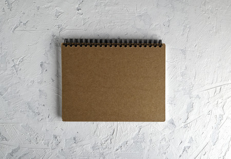 notebook on a black iron spring with brown empty sheets on a white background, close up