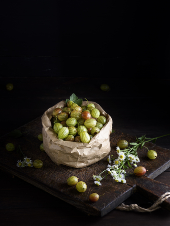 ripe green gooseberry in a paper bag on a brown wooden board,  copy spaceの写真素材