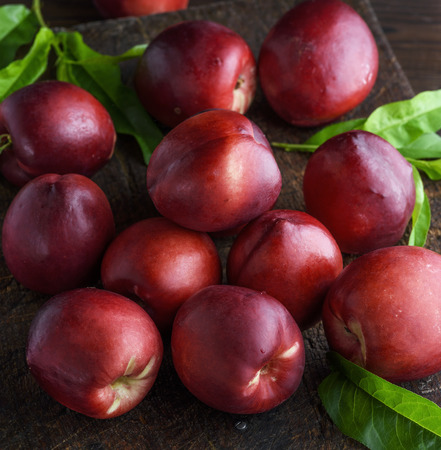 red ripe peaches nectarine on a brown wooden board,  close upの写真素材