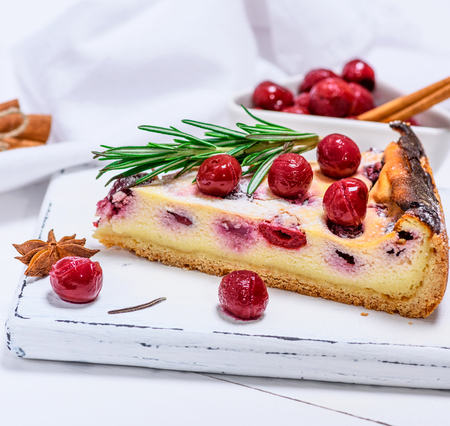 slice of cheesecake from cottage cheese and marinated cherries on a white wooden board, close upの写真素材
