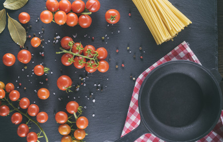 empty cast iron round frying pan and ripe red cherry tomatoes , top viewの写真素材