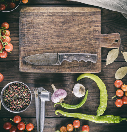 old brown empty kitchen cutting and fresh red cherry tomatoes with green chili on the table, top viewの写真素材