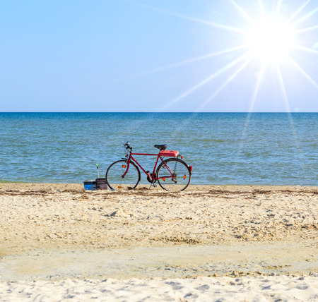 old red bicycle standing by the sea on a summer dayの写真素材