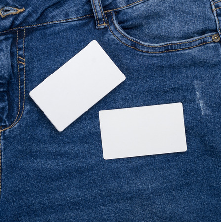 blank white paper business cards on a blue jeans background, close up