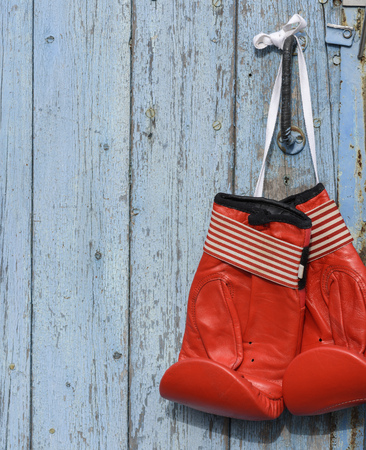 pair of red leather boxing gloves hanging on an old blue wooden wall, copy spaceの写真素材