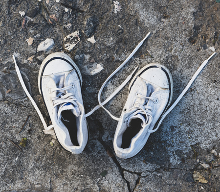 pair of old worn white sneakers with laces on asphalt, top viewの写真素材
