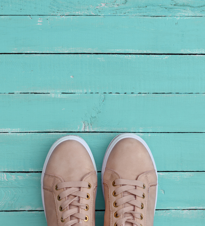 pink pair of female leather sneakers with laces on a blue wooden backgroundの写真素材