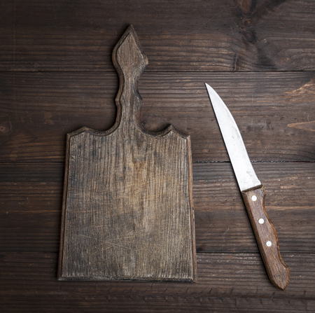 very old empty kitchen brown cutting board with handle and knife on the table, top viewの写真素材