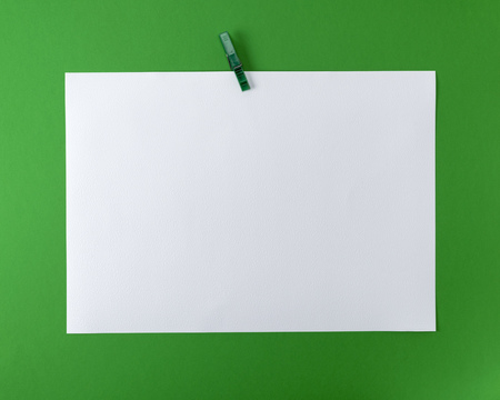 white blank drawing sheet on green plastic clothespin, green backgroundの写真素材