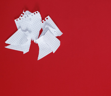 torn to pieces a white sheet of paper on a red background, copy spaceの写真素材