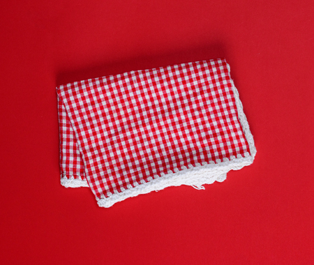 folded red cotton kitchen towel in the box on a red background, top view