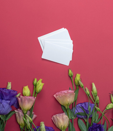 fresh blooming flowers Eustoma Lisianthus and empty paper card on red  background, top view, copy spaceの写真素材