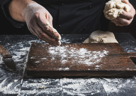 chef in black jacket, kneads dough made from white wheat flour, close up