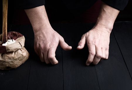 two male hands over a black wooden table, concept of kneading doughの写真素材