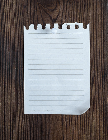 empty notepad paper attached with a button on a brown wooden surfaceの写真素材