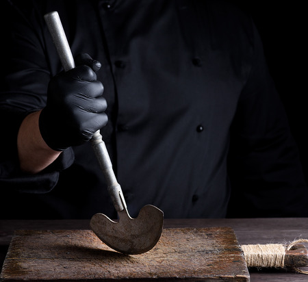 chef in black clothes holds in his hand a metal old knife for meat and vegetablesの写真素材