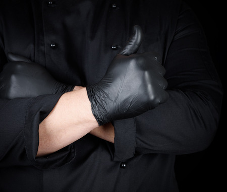 cook in black uniform crossed his arms and shows gesture like, black background, thumb upの写真素材