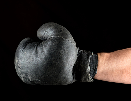 very old boxing glove dressed on man's hand, black backgroundの写真素材