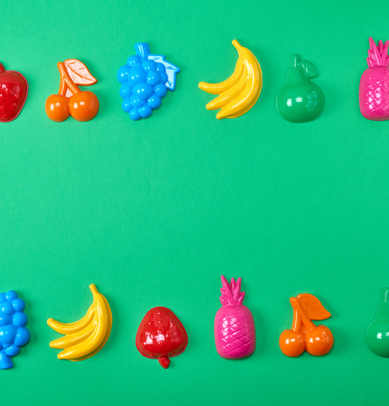 multicolored plastic toys fruits on a green background, copy spaceの写真素材