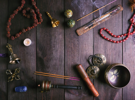Tibetan singing bowl and other religious ritual instruments for meditation on a brown wooden background, top view, copy spaceの写真素材