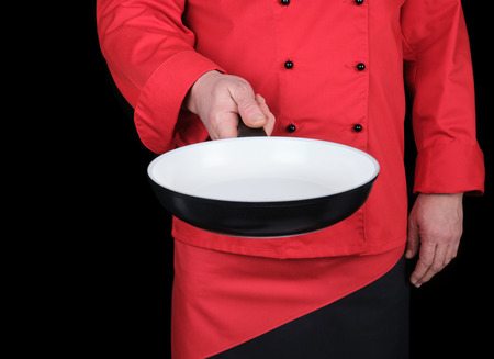 cook in red uniform holding an empty round white frying pan, black backgroundの写真素材