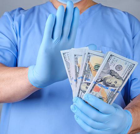 doctor in blue uniform and datex gloves holds a lot of paper money and with a gesture of hand shows...
