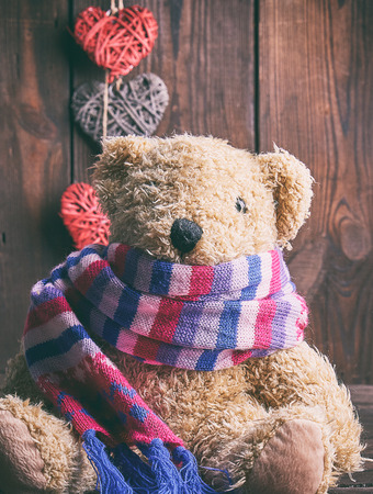 brown soft teddy bear sit on a brown wooden background, close upの写真素材