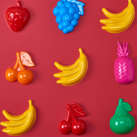 multicolored plastic childrens toys in the form of fruit on a red backgroundの写真素材
