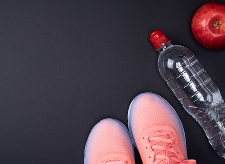 pink sports sneakers and a  water bottle on a black background, top viewの写真素材