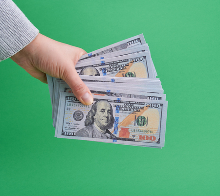 hand holding paper money on a green background, close up の写真素材
