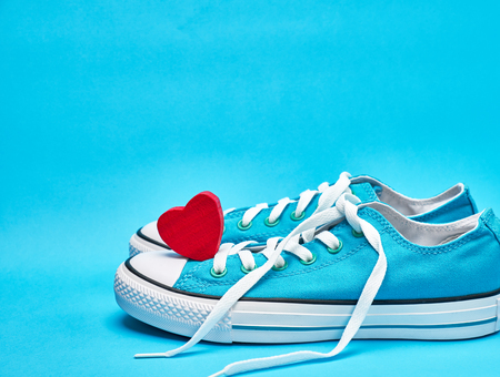 pair of blue textile sneakers with white untied laces and  red heart, copy spaceの写真素材