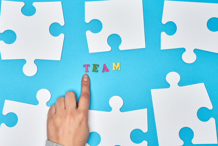 white big puzzles on a blue background,  inscription team, the concept of recruitment in the companyの写真素材