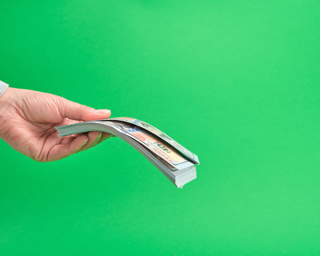 hand holding paper money on a green background, close up