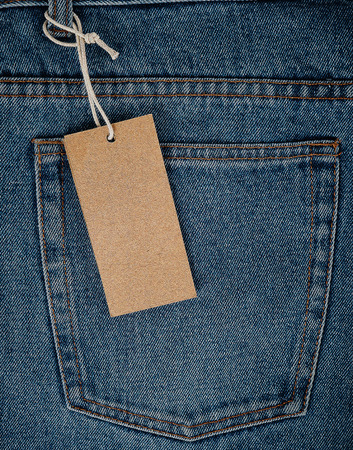 tied on a rope is an empty rectangular brown paper tag on blue jeans, full frameの写真素材