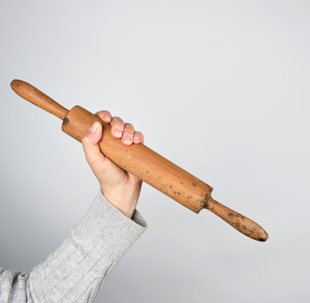 hand holding old wooden rolling pin on a gray backgroundの写真素材