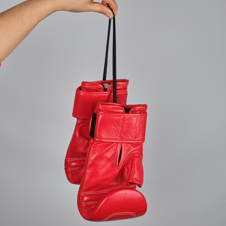 pair of red leather boxing gloves hang on a string, gray backgroundの写真素材
