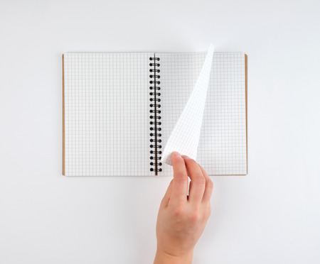 empty open notebook in a cell and a female hand, white  background, top viewの写真素材