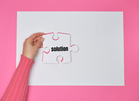 female hand holding white puzzle with the word solution, process of closing the missing element , conceptual business backgroundの写真素材