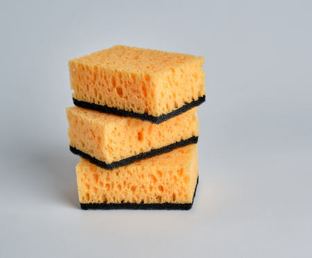 stack of yellow kitchen sponges for washing dishes on a white backgroundの写真素材
