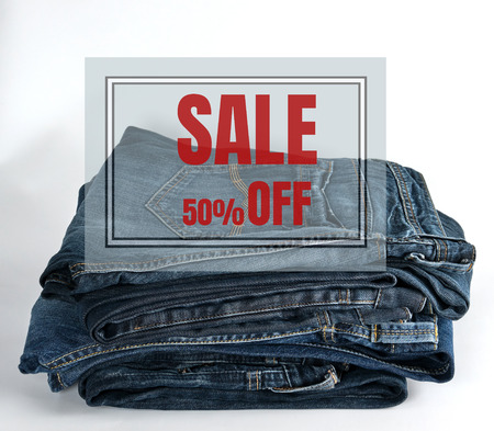 stack of blue jeans on white background, concept of seasonal sale minus fifty percent discountの写真素材